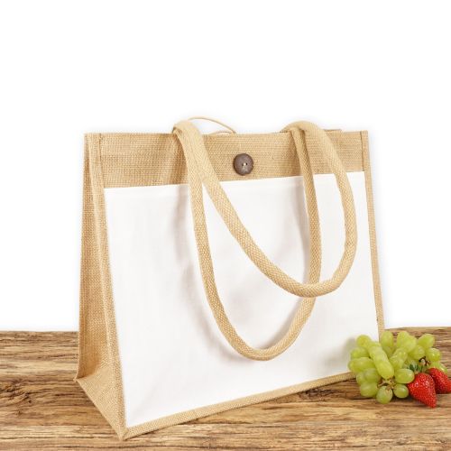 Einkaufstasche aus Jute mit weißer Fronttasche zum Bedrucken, naturfarben mit Seiten-Bodenfalte, mittelgroß und mit langen Tragegriffen auf Holz.