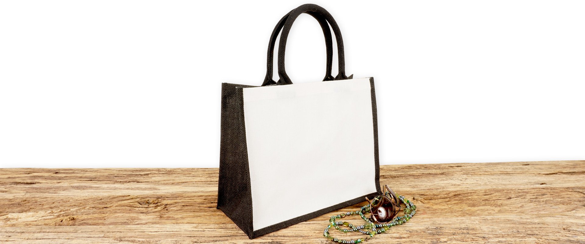 Einkaufstasche aus Jute und Baumwolle zum Bedrucken, klein, schwarz-weiß mit Seiten-Bodenfalte und mit kurzen runden Tragegriffen auf Holz.