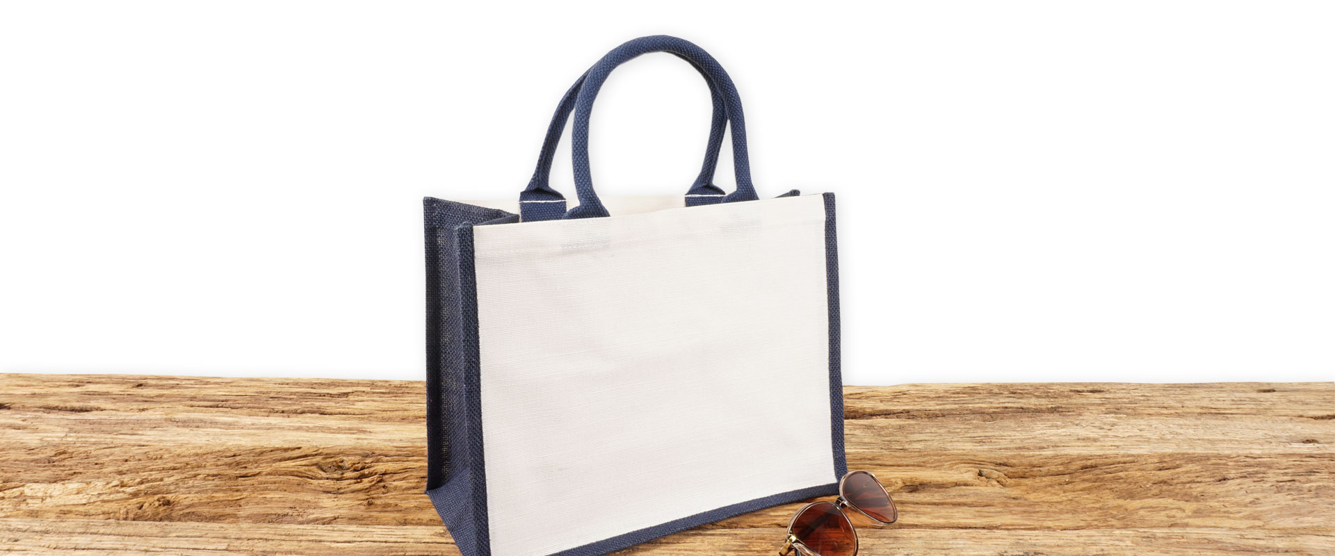 Einkaufstasche aus Jute und Baumwolle zum Bedrucken, klein, blau-weiß mit Seiten-Bodenfalte und mit kurzen runden Tragegriffen auf Holz.